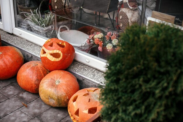 Pumpkins with scary faces in city street holiday decoration of store fronts and buildings halloween street decor space for text trick or treat happy halloween autumn market in town