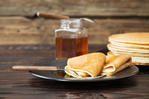 Puncakes with honey and cup of tea on old wooden table