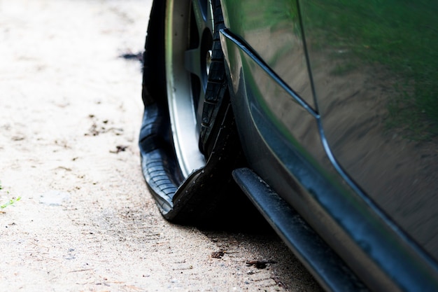 道路上の現代の車のパンクしたホイール。車のタイヤのパンク