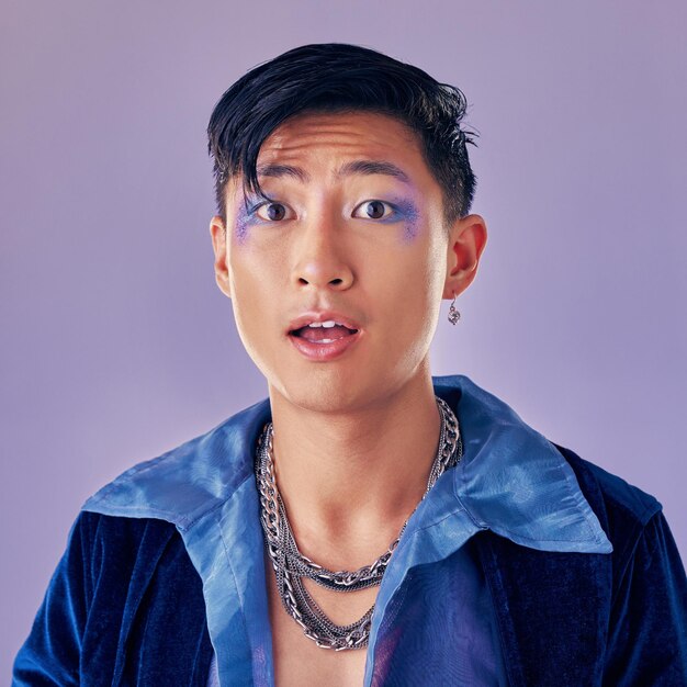 Foto trucco punk e faccia in shock wow e sorpresa con un uomo gay su uno sfondo da studio viola per la moda futura o retrò cosmetici cyberpunk e modello estetico lgbtq per ritratto vaporwave