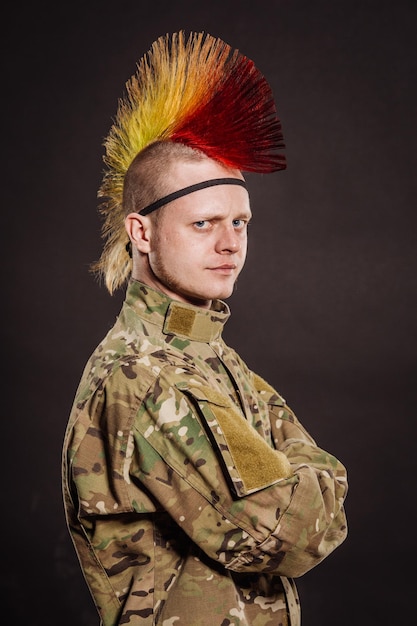 Punk rocker in military camouflage uniform with arms crossed\
military lifestyle people concept