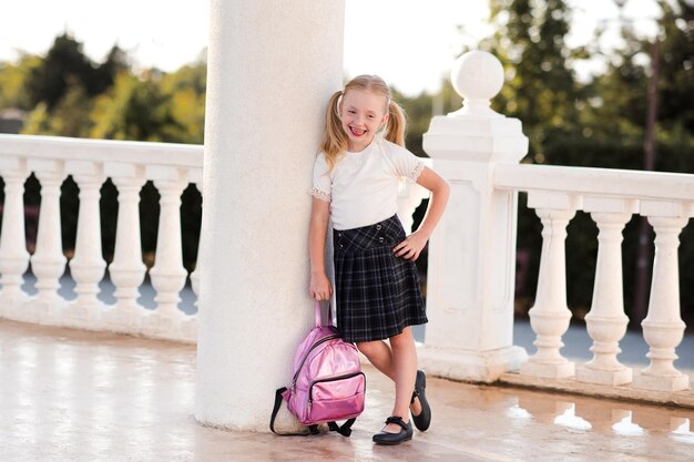 Photo pupil kid girl 4-5 year old posing outdoors looking at camera back to school