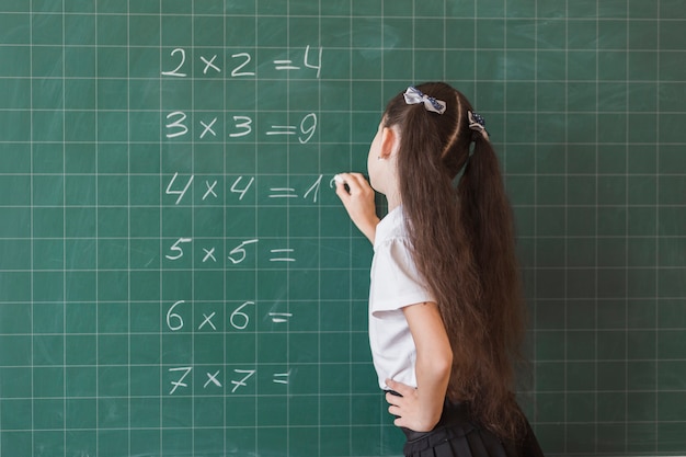 Pupil making math exercise on chalkboard