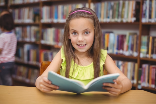 Pupil reading book at desk in library