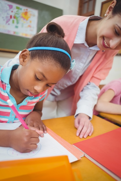 Pupil and teacher at desk in classroom