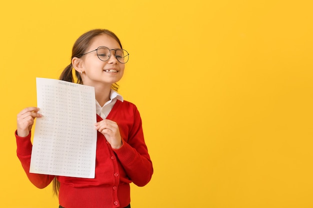 Pupil with answer sheet for school test on yellow