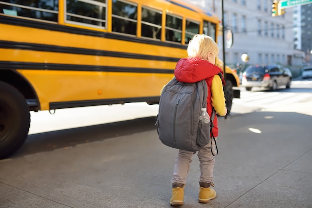 Pupil with schoolbag near yellow school bus 