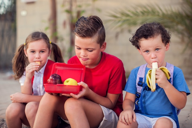 Alunni che hanno uno spuntino all'aperto. concetto di bambini, educazione e nutrizione