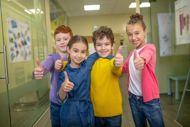 Pupils laughing and hugging each other standing in the school corridor