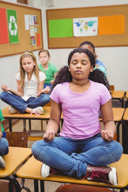 Pupils meditating on classroom desks