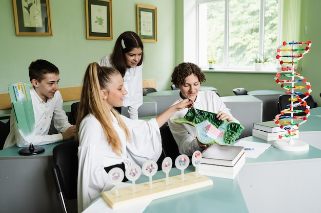 Foto alunni che mostrano e studiano modelli di dna e cellule animali sul tavolo in classe istruzione presso la scuola di biologia e chimica