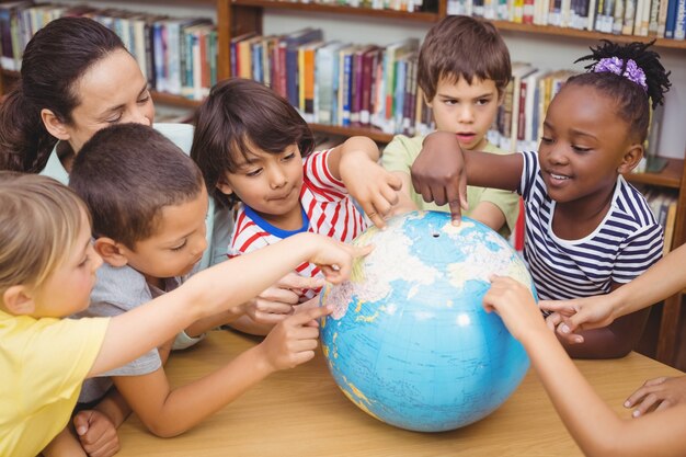 Pupils and teacher looking at globe in library