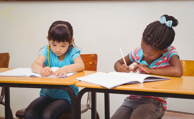 Pupils writing in notepad at their desk