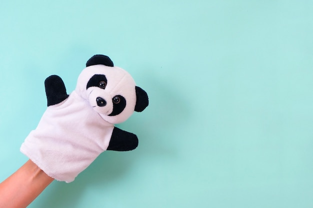Puppet theater toys on a hand on a turquoise background. Childrens entertainment concept. panda