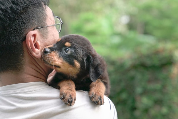 大人の男の肩にしがみついている子犬