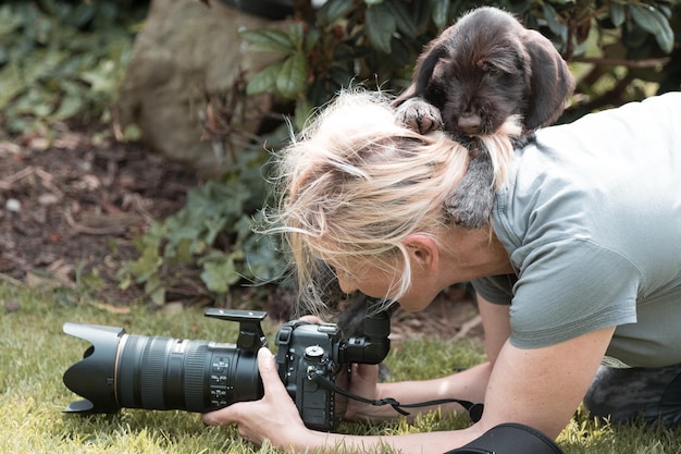 Foto puppy op volwassen vrouw fotografeert met digitale camera in het park