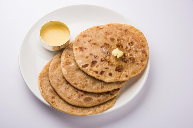 Puran poli, also known as holige, is an indian sweet flatbread consumed mostly during holi festival. served in a plate with pure ghee over colourful or wooden background. selective focus