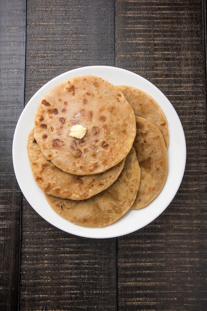 Puran Poli, also known as Holige, is an Indian sweet flatbread consumed mostly during Holi festival. Served in a plate with pure Ghee over colourful or wooden background. Selective focus