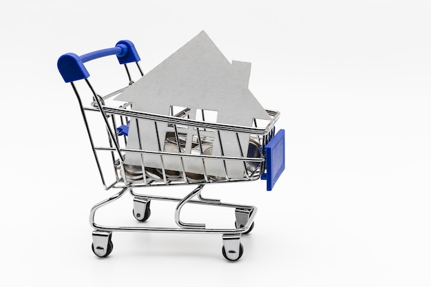 Purchase and sale of housing. Mortgage for the purchase of a house. Rental Property. Mock up of a paper house in in a coin shop cart. Close-up. Copy space. Good deal.