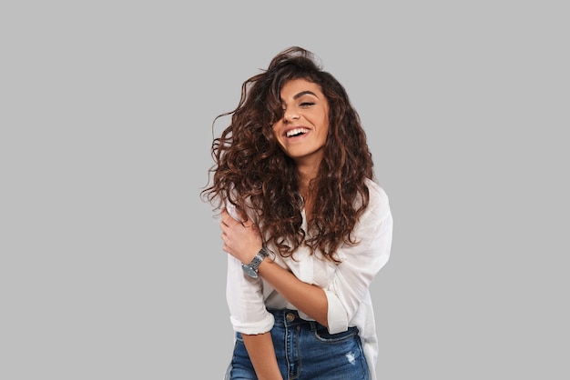 Pure beauty. Attractive young woman smiling while standing against grey background