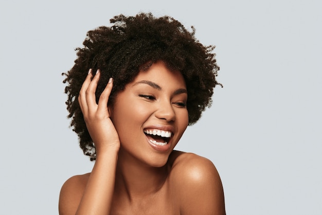 Pure beauty. Beautiful young African woman looking away and smiling while standing against grey background