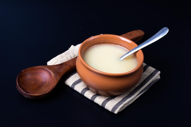 Pure cow ghee in ceramic bowl on black background with ghee spoon in hand