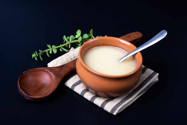 Pure cow ghee in ceramic bowl on black background with ghee spoon in hand