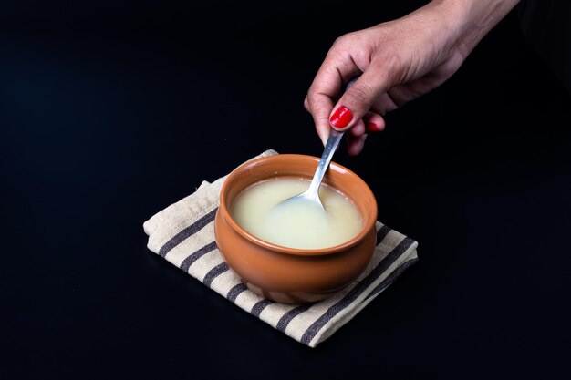 Pure cow ghee in ceramic bowl on black background with ghee spoon in hand