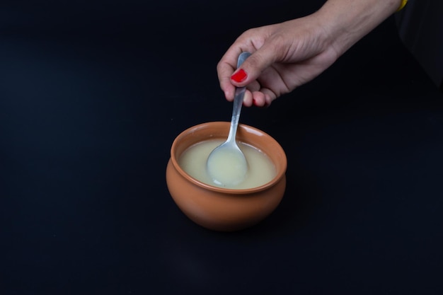 Pure cow ghee in ceramic bowl on black background with ghee spoon in hand