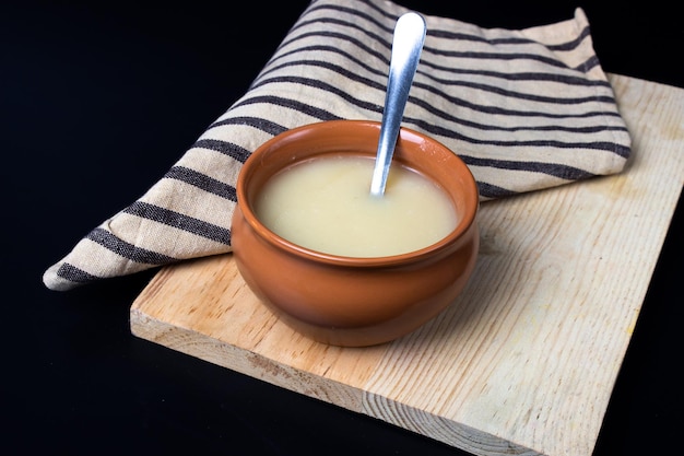 Pure cow ghee in ceramic bowl on black background with ghee spoon in hand