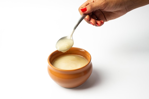 Pure cow ghee in ceramic bowl on white background with ghee spoon in hand