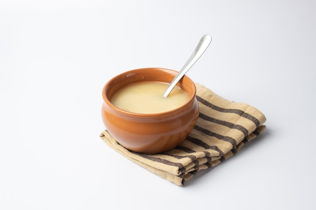 Pure cow ghee in ceramic bowl with steel spoon on white background