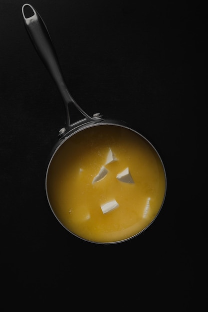 Photo pure or desi ghee also known as clarified liquid butter pure or desi ghee is prepared in a steel pan top view