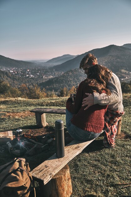 순수한 감정. 산에서 평온한 시간을 보내는 동안 모닝 커피를 마시는 아름다운 젊은 부부