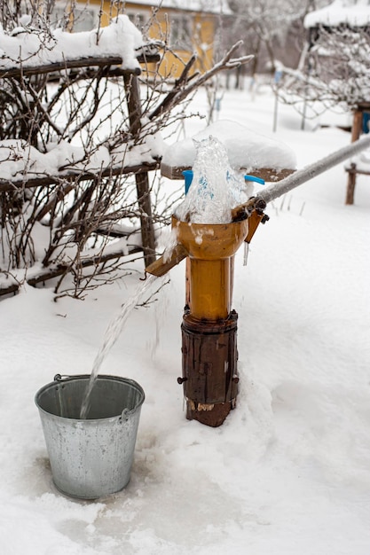 Pure fresh drinking water is poured into a bucket using a hand pump