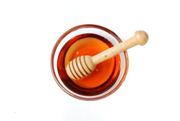 Pure honey glass bowl with honey wooden spoon isolated on white background