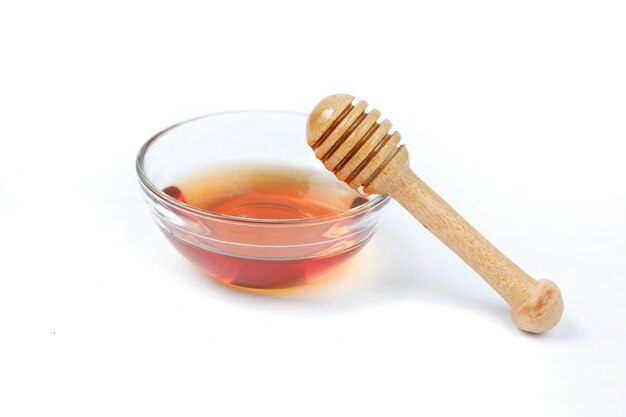 Pure honey glass bowl with honey wooden spoon isolated on white background