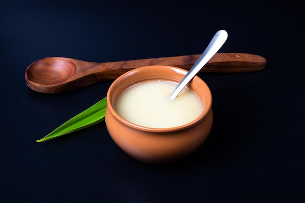 Pure koe ghee in keramische kom op zwarte achtergrond met ghee-lepel in de hand