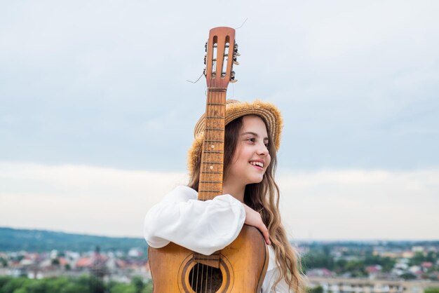 Pure schoonheid jeugdgeluk muziek en zang volg je eigen stijl voel de inspiratie vrolijk kind met akoestische gitaar casual mode-stijl voor mooi kind tienermeisje gitaar spelen