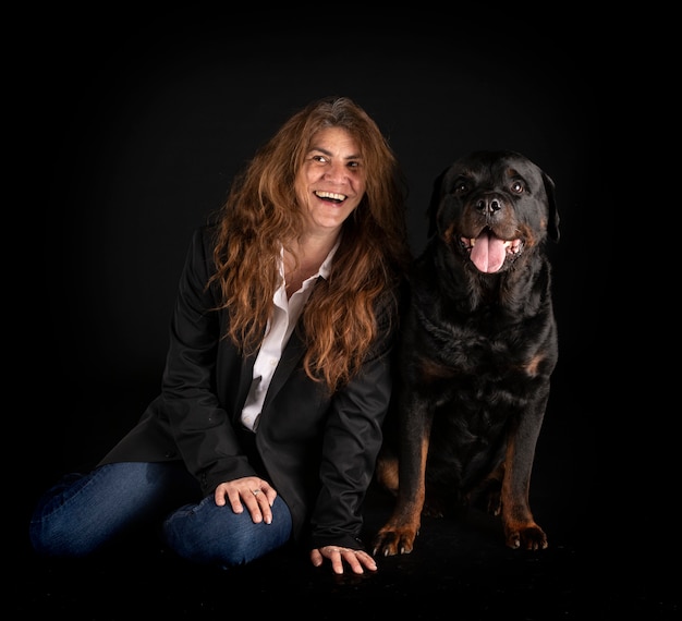 Purebred rottweiler and woman in front of black surface