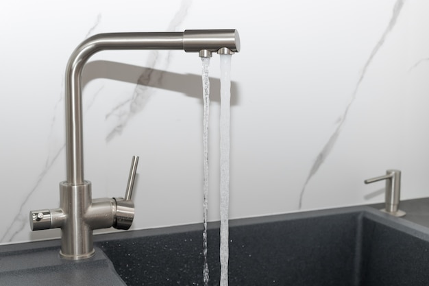 Photo purified and clean water pours from modern kitchen faucet household filtration system