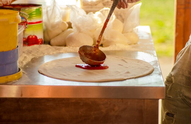 Puring the tomato sauce on pizza dough