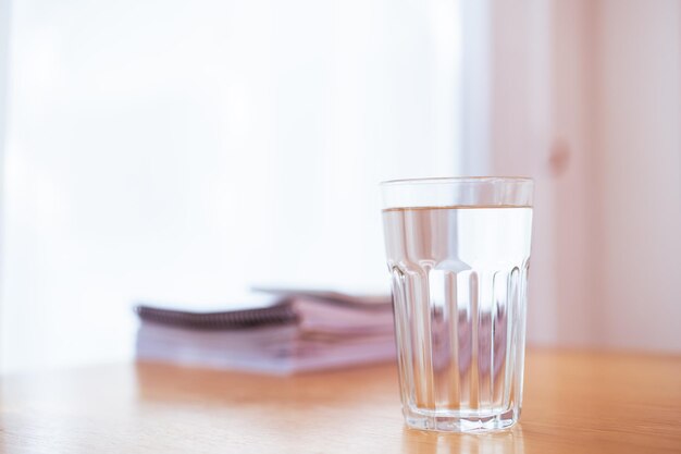 Purity drinking water in a drinking glass on the wooden table\
in office close up with copyspace work life balance in healthy\
people in modern working lifestyles heath care and wellbeing\
concept