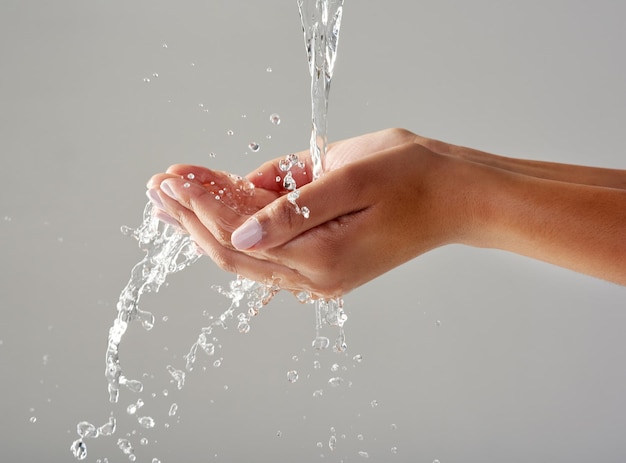 Purity in the palm of your hands Cropped shot of hands held out under a stream of water against a grey background