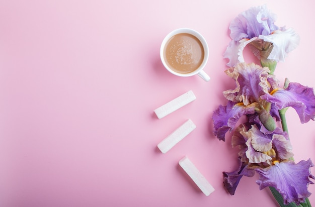 Purpere irisbloemen en een kop van koffieachtergrond met copyspace