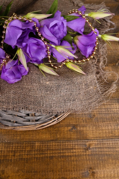 Purple artificial eustoma on sackcloth on color wooden table on bright background