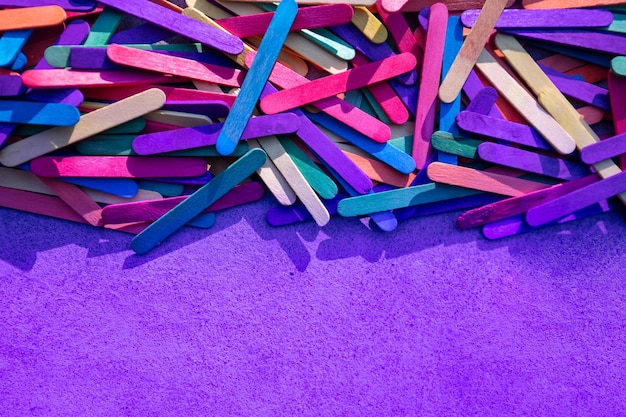 木製のカラフルな棒の束と紫色の背景