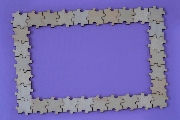 Photo purple background with a frame made of wooden puzzles copy space for text flat lay top view