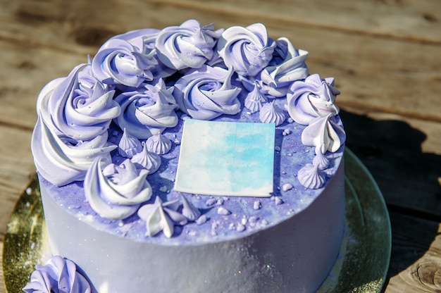 クリーム色の花と紫のバースデーケーキをクローズアップ。結婚式のお菓子、装飾的なステッカー、トップビューで飾られたブルーベリーケーキ