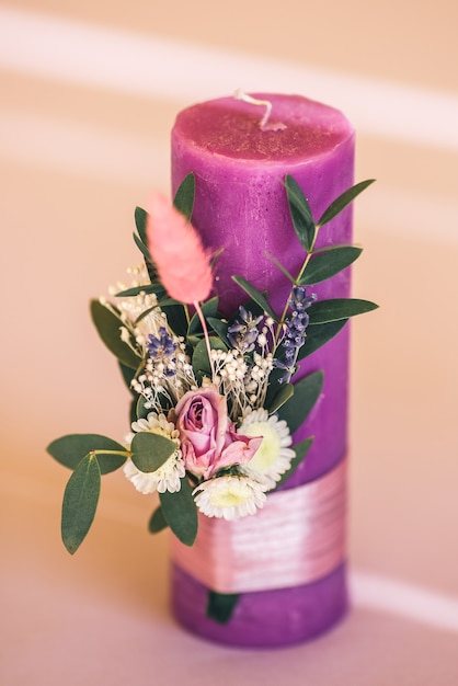 Purple candle decorated with flowers for the holiday